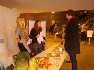 Die Doktorandinnen Lucie Chamlian und Maria Grewe lassen Besucher des Forschungstags in einem Nachhaltigkeitsspiel Lebensmittel in einen Kühlschrank sortieren.